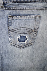 22890707 - close up image of denim jeans pocket with a ripped hole